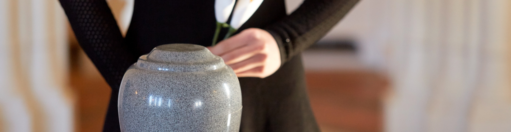 Kobieta stoi za urną trzymając w dłoniach białe kalie